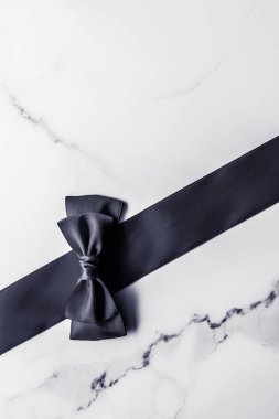 Siyah ipek kurdele ve yay mermer arka planda, yatık