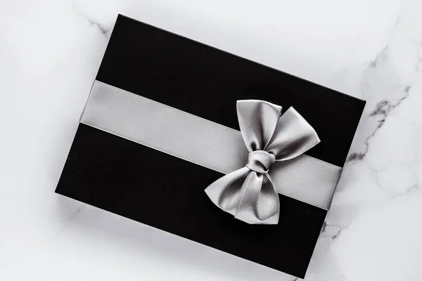 Роскошные праздничные подарки с серебряной шелковой лентой и луком на мраморе b — стоковое фото