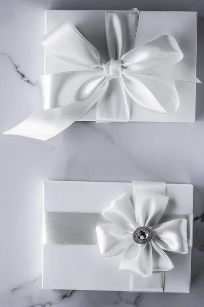 Luxury wedding gifts with silk bow and ribbons on marble backgro