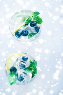 Arka planda buz ve parlayan kar ile kış tatili kokteyli,