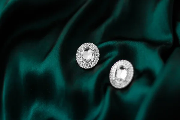 Роскошные бриллиантовые серьги на темно-изумрудно-зеленом шелке, праздничный глэм — стоковое фото
