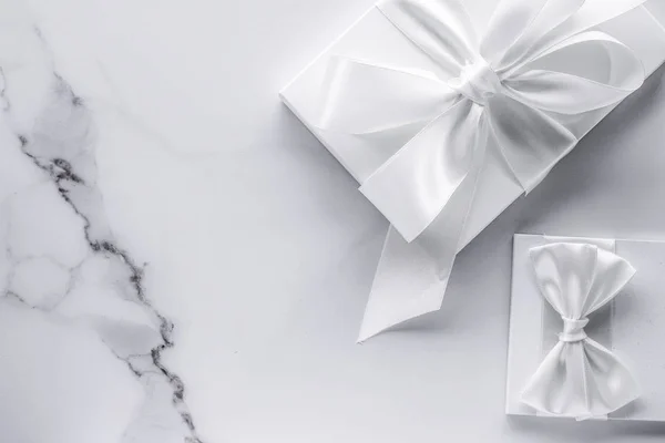 Розкішні весільні подарунки з шовковим бантом та стрічками на мармуровому фоні — стокове фото