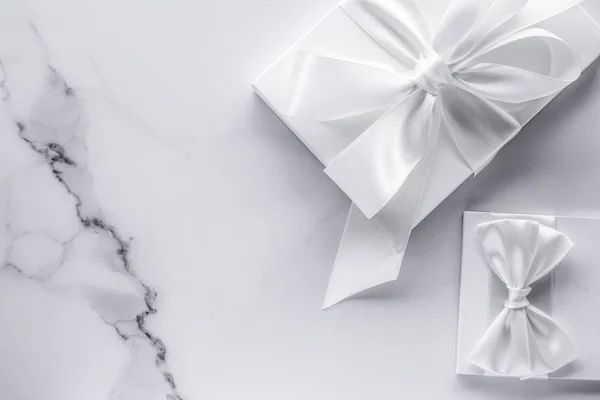 Luxury wedding gifts with silk bow and ribbons on marble backgro