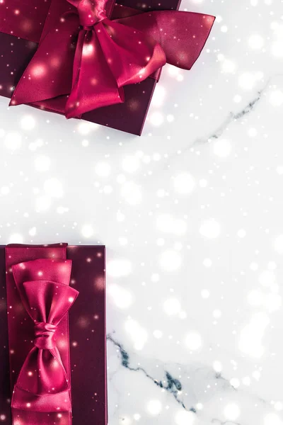 Winter holiday gifts with cherry silk bow and glowing snow on fr — Stock Photo, Image