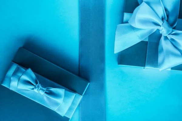Розкішні святкові подарунки з шовковою стрічкою та бантом на синьому фоні — стокове фото