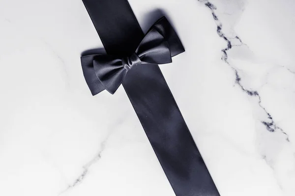 Black silk ribbon and bow on marble background, flatlay — Stock Photo, Image