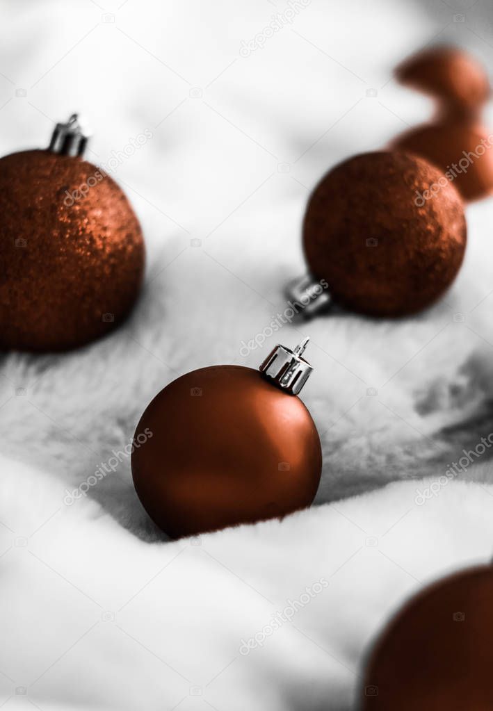 Chocolate brown Christmas baubles on white fluffy fur backdrop, 