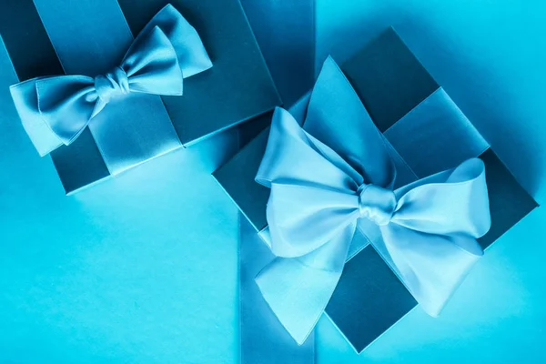 Presentes de férias de luxo com fita de seda e arco no fundo azul — Fotografia de Stock
