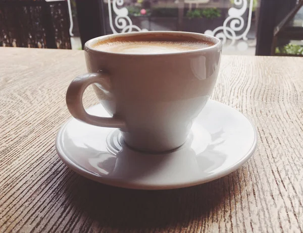Ένα φλιτζάνι ζεστό καπουτσίνο σε μια καφετέρια, καφέ σε ένα ξύλινο τραπέζι που — Φωτογραφία Αρχείου