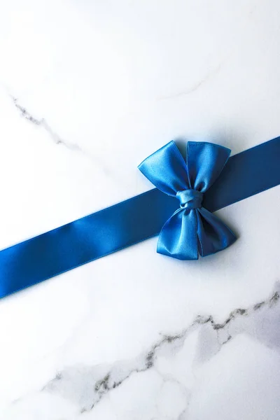 Modrá hedvábná stuha a luk na luxusním mramorovém pozadí, prázdninový FL — Stock fotografie