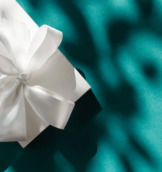 Luxury holiday white gift box with silk ribbon and bow on emeral