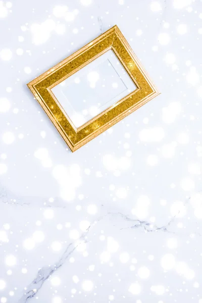 Golden photo frame and glowing glitter snow on marble flatlay ba — Stock Photo, Image