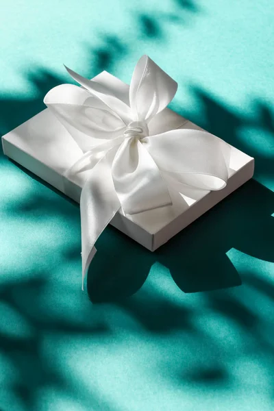 Luxury holiday white gift box with silk ribbon and bow on emeral