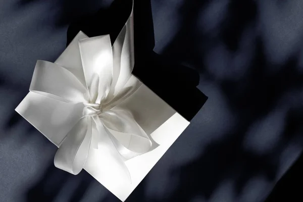 Luxury holiday white gift box with silk ribbon and bow on black