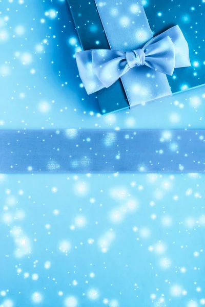 Prezenty zimowe wakacje i świecący śnieg na zamarzniętym niebieskim tle, — Zdjęcie stockowe