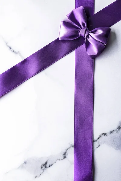 Фиолетовая шелковая лента и лук на роскошном мраморном фоне, праздник — стоковое фото
