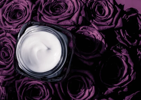 Crema facial hidratante de piel sobre rosas púrpuras flores, piel de lujo — Foto de Stock