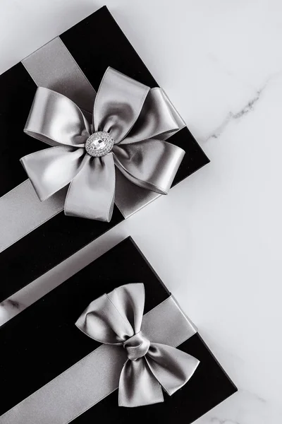 Luxury holiday gifts with silver silk ribbon and bow on marble b