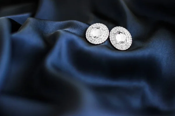 Luxury diamond earrings on dark blue silk background, holiday gl — Stock Photo, Image