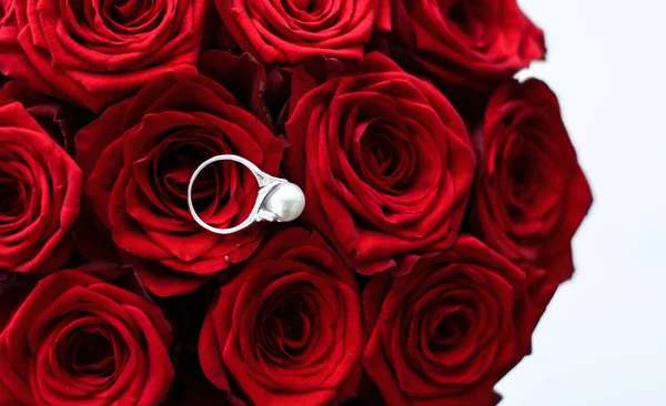Hermoso anillo de perlas de oro blanco y ramo de rosas rojas, de lujo — Foto de Stock