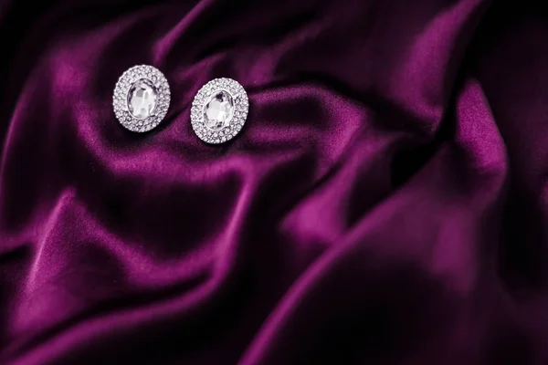 Розкішні діамантові сережки на темно-рожевій шовковій тканині, святковий гламур — стокове фото