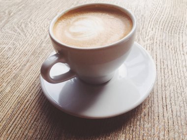 Bir kafeteryasıcak kapuçino Fincan, ahşap bir masada kahve i