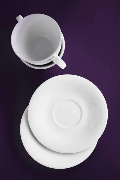 Set stoviglie bianche, tazza vuota su fondo piatto viola — Foto Stock