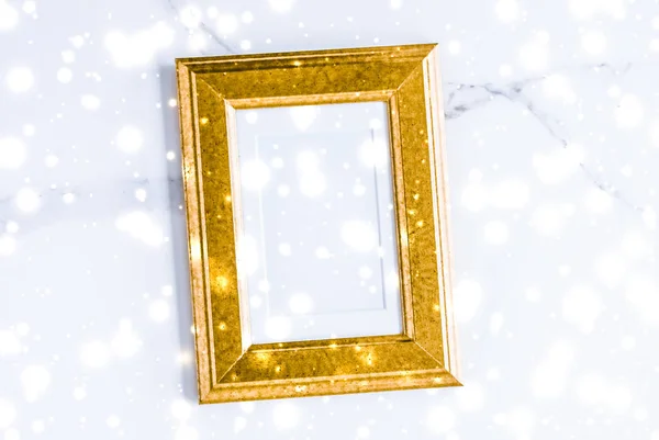 Golden photo frame and glowing glitter snow on marble flatlay ba — Stock Photo, Image