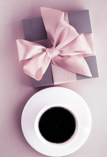 Luxury gift box and coffee cup on blush pink background, flatlay