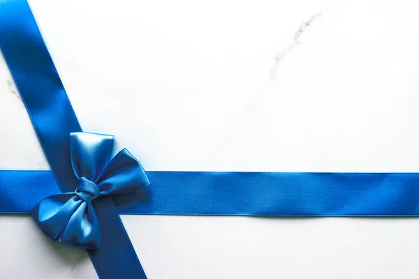Блакитна шовкова стрічка і лук на розкішному мармуровому фоні, святковий фл — стокове фото