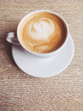 Bir kafeteryasıcak kapuçino Fincan, ahşap bir masada kahve i