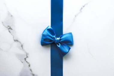 Mavi ipek kurdele ve lüks mermer arka plan üzerinde yay, tatil fl