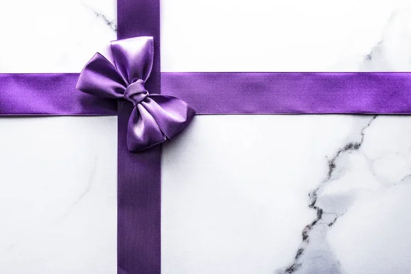 Purple silk ribbon and bow on luxury marble background, holiday