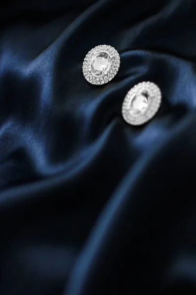 Розкішні діамантові сережки на темно-синьому шовковому фоні, святковий глем — стокове фото