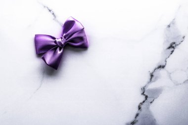 Mor ipek kurdele ve lüks mermer arka plan üzerinde yay, tatil 