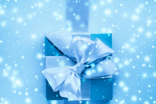 Зимові святкові подарунки та сяючий сніг на замерзлому синьому фоні , — стокове фото