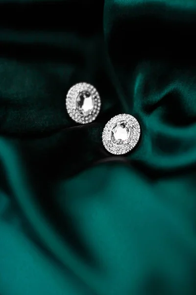 Luxury diamond earrings on dark emerald green silk, holiday glam — Stock Photo, Image