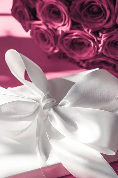 Luxury holiday silk gift box and bouquet of roses on pink backgr