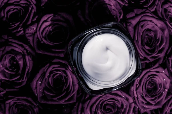 Crema facial hidratante de piel sobre rosas púrpuras flores, piel de lujo —  Fotos de Stock