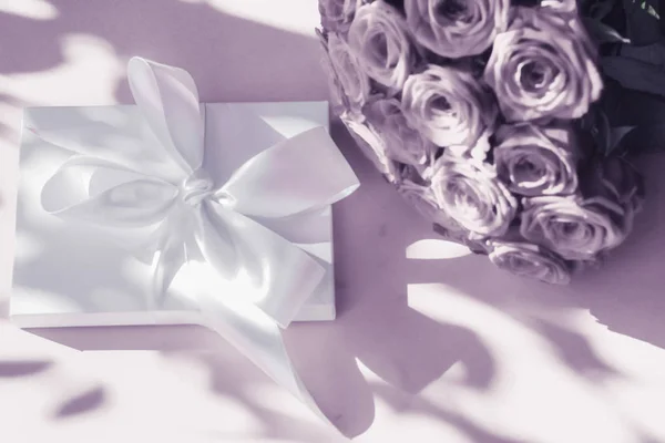 Luxury holiday silk gift box and bouquet of roses on purple back