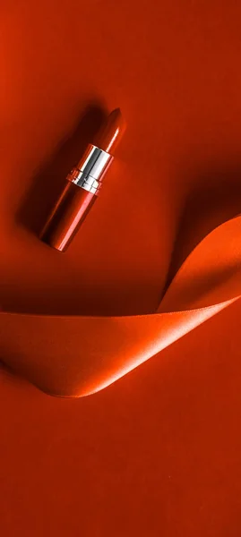 Rouge à lèvres de luxe et ruban de soie sur fond de vacances orange, ma — Photo