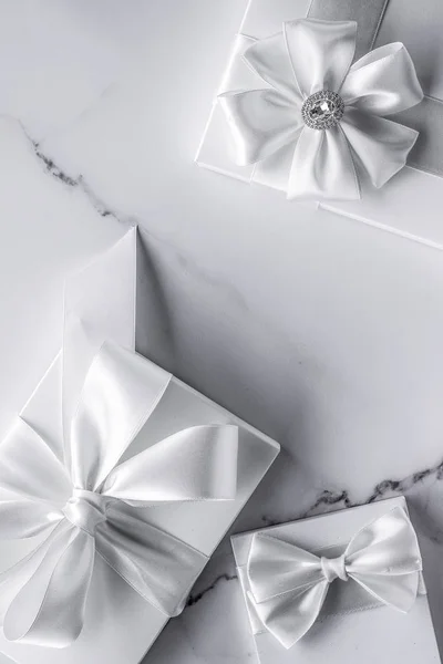 Luxury wedding gifts with silk bow and ribbons on marble backgro