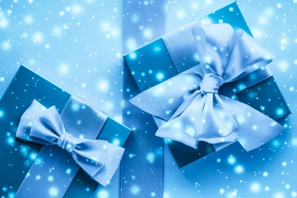 Winterurlaubsgeschenke und glühender Schnee auf gefrorenem blauen Hintergrund, — Stockfoto