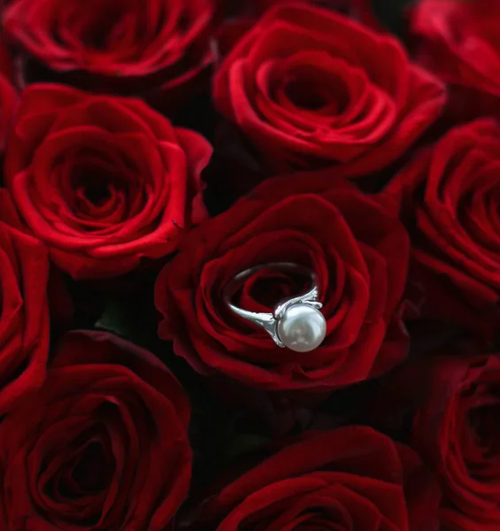 Beautiful white gold pearl ring and bouquet of red roses, luxury — Stock Photo, Image