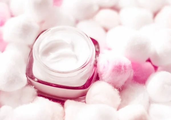 Luxury face cream for sensitive skin and pink cotton balls on ba
