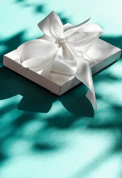 Luxury holiday white gift box with silk ribbon and bow on emeral