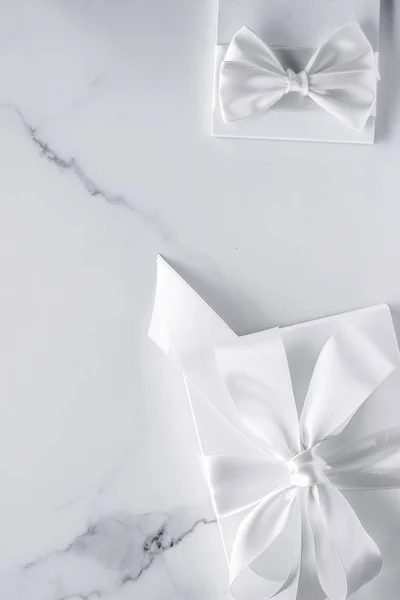 Luxury wedding gifts with silk bow and ribbons on marble backgro