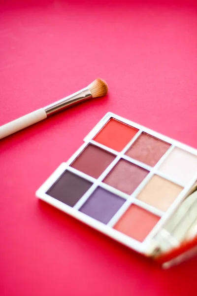 Palette de fards à paupières et pinceau de maquillage sur fond rouge, eye shado — Photo