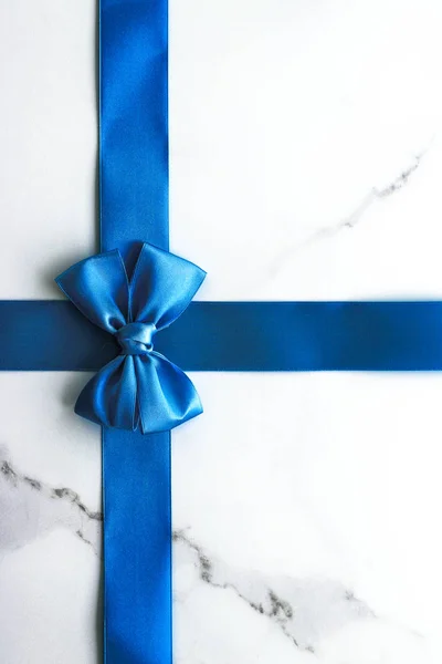 Fita de seda azul e arco no fundo de mármore de luxo, feriado fl — Fotografia de Stock