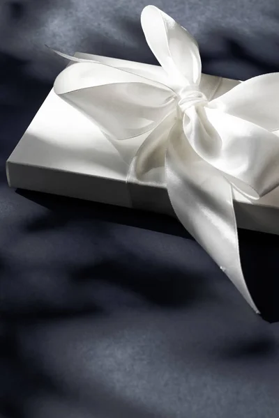 Розкішна святкова біла подарункова коробка з шовковою стрічкою та бантом на чорному — стокове фото